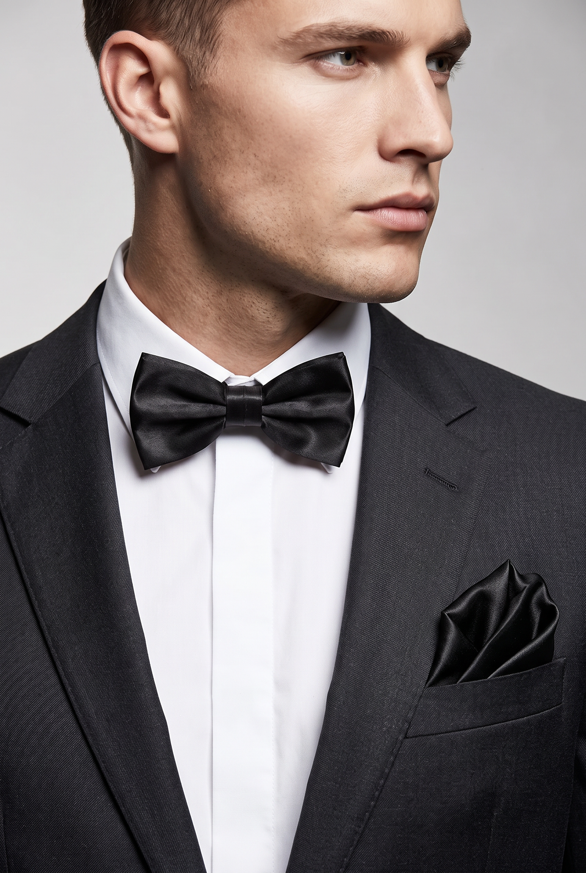 Men wearing a black satin bow tie and matching pocket square with a suit