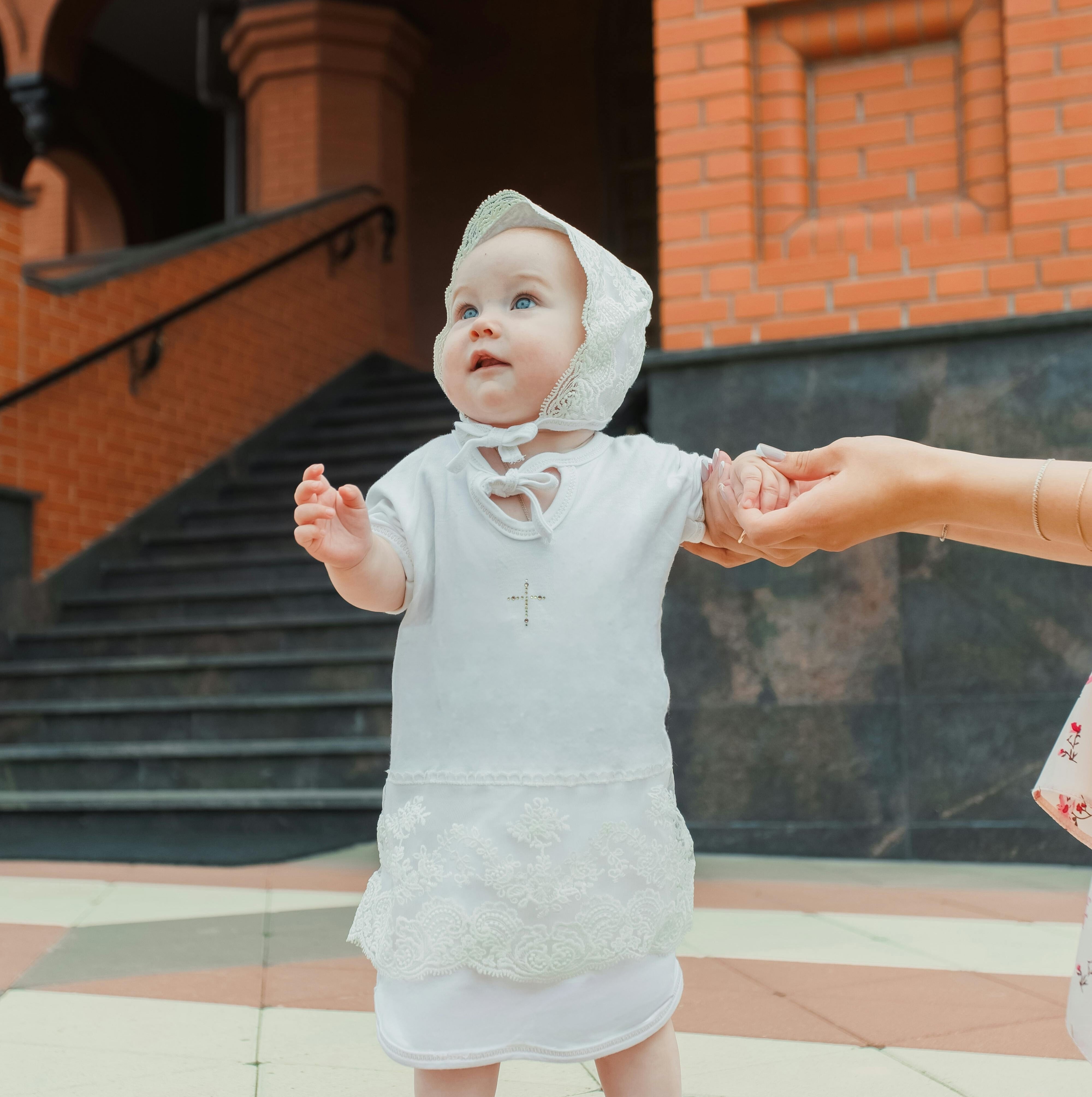 Baby wearing a baptism outfit with a bonnet.