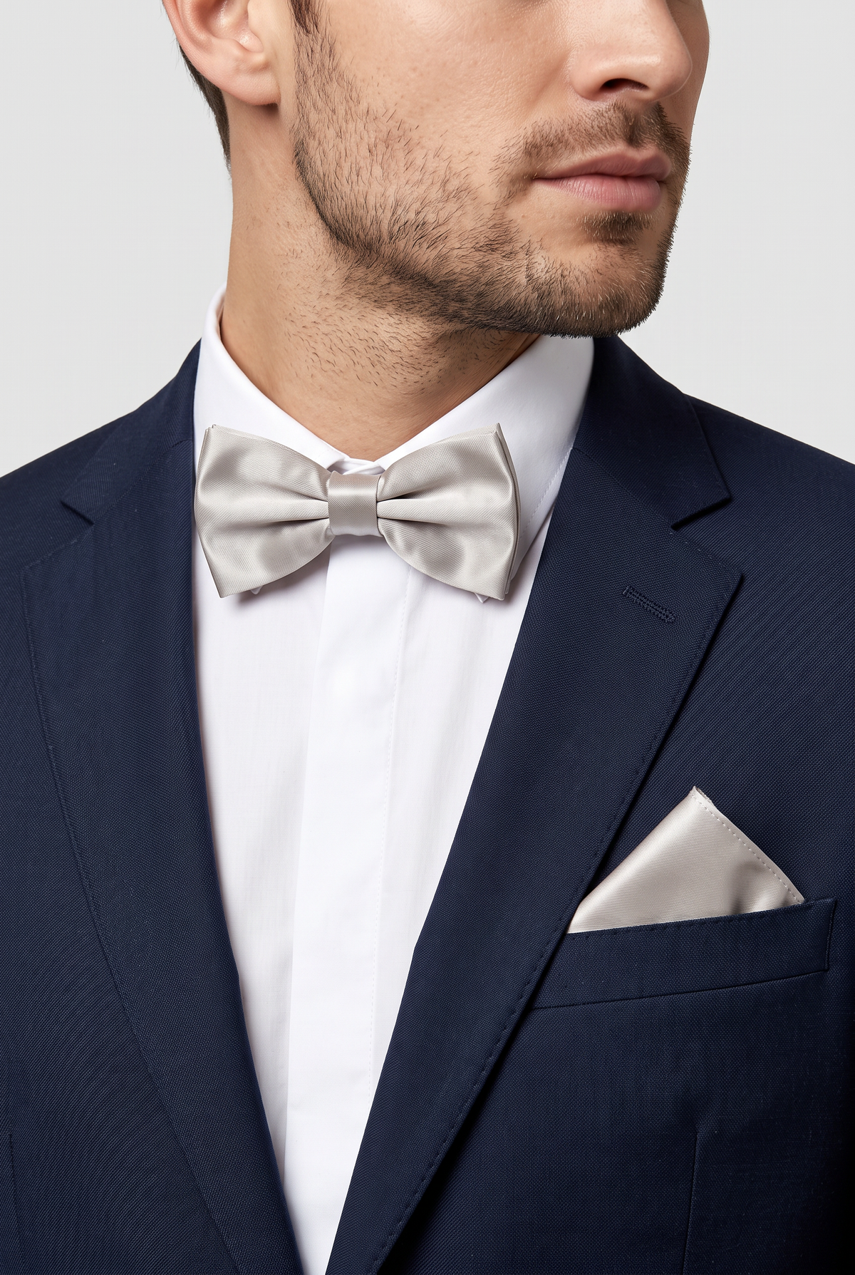 Men wearing a silver satin bow tie and matching pocket square with a suit