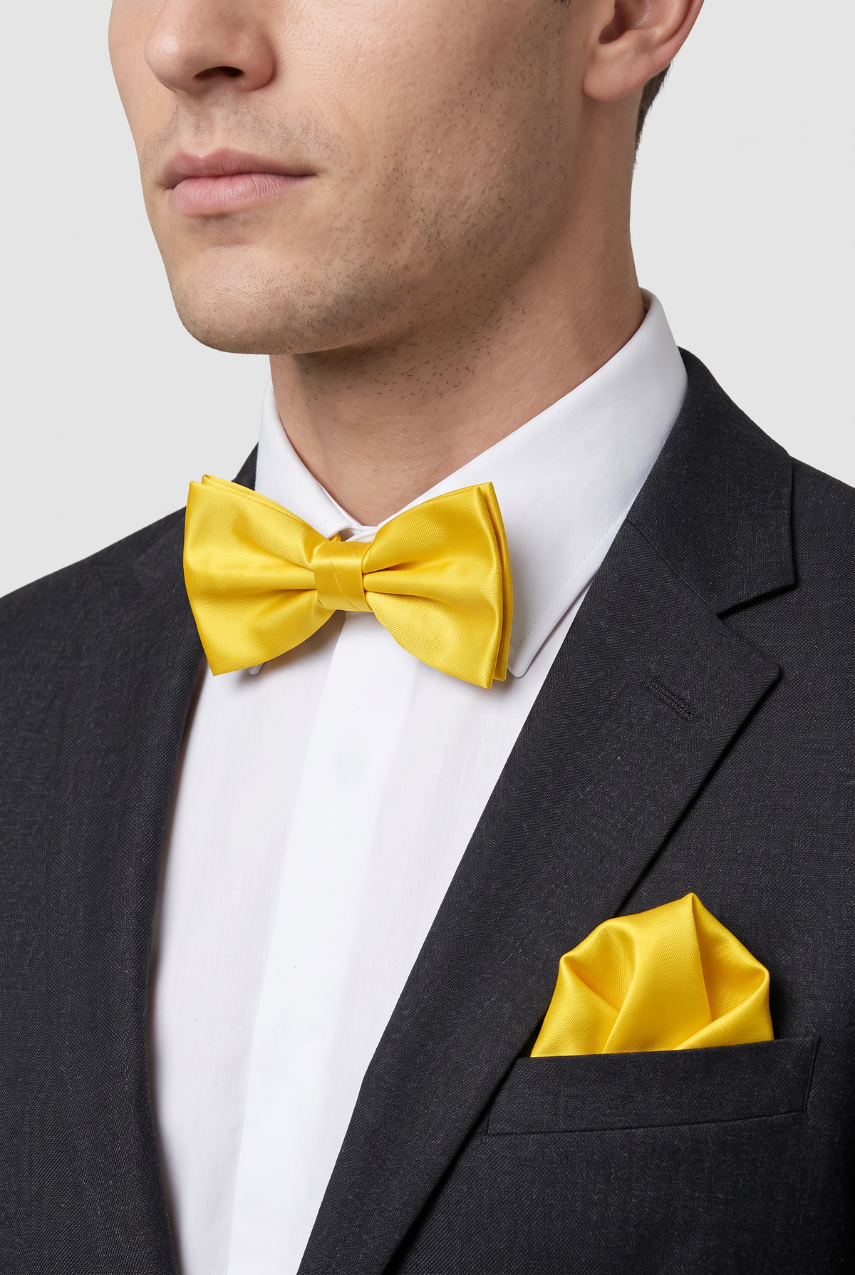 Men wearing a yellow satin bow tie and matching pocket square with a suit